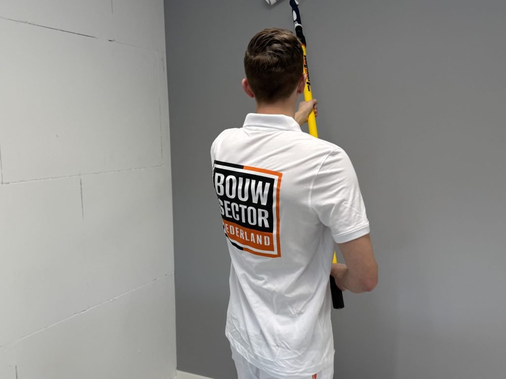 Schilder van Bouwsector Nederland rolt een grijze wand naast een witte wand van kalkzandsteen